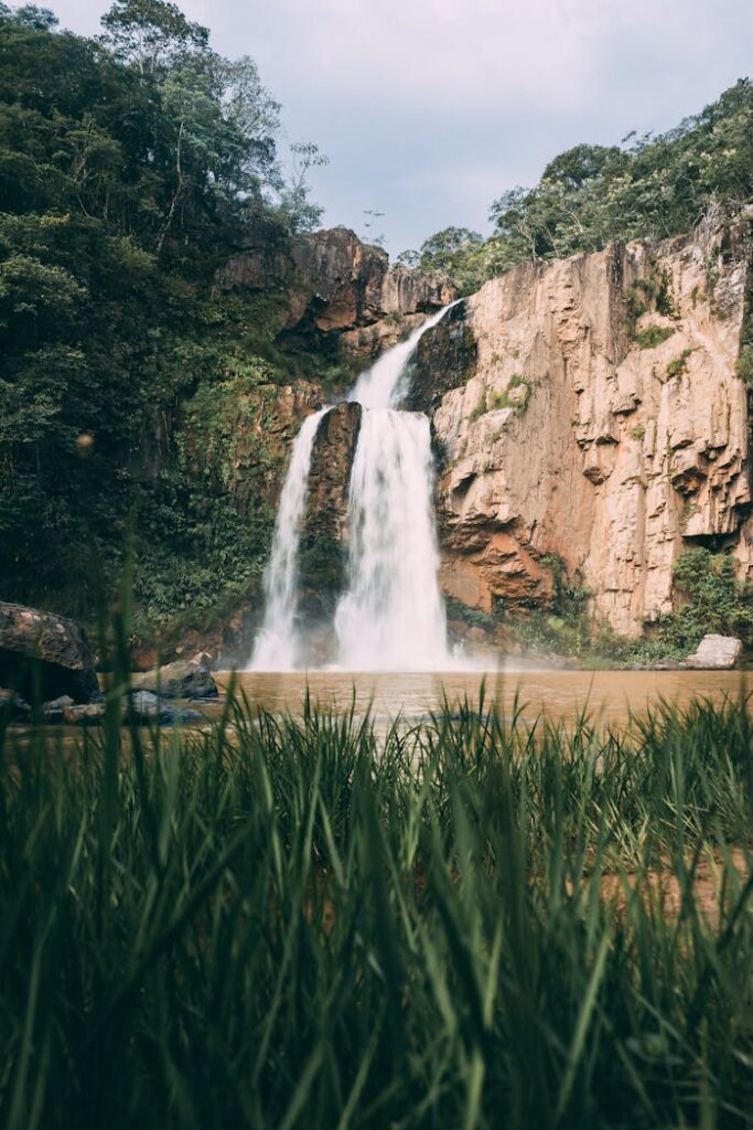 pexels-photo-3571592 Majestic waterfall cascading down rocky cliffs surrounded by lush tropical greenery.